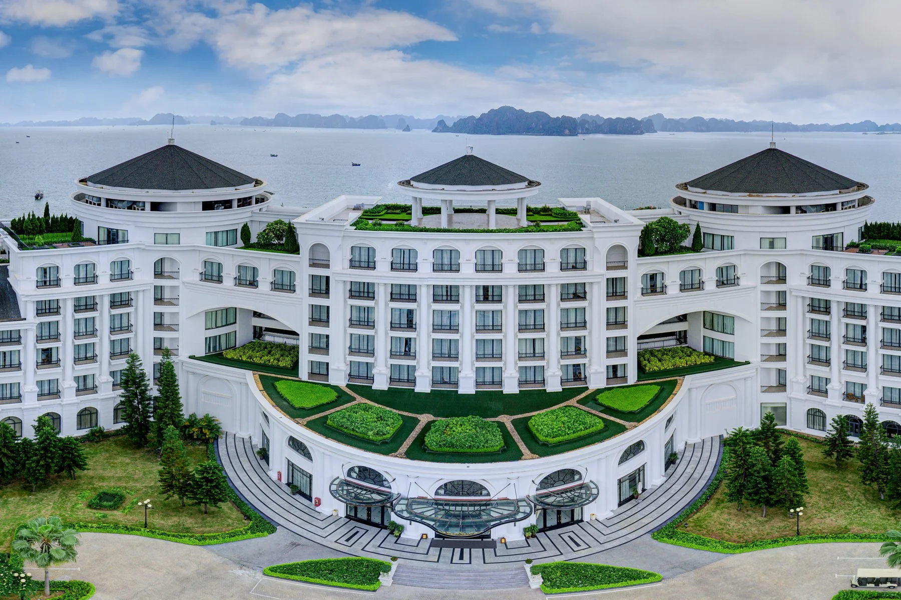 Panorama khu nghỉ dưỡng ven vịnh với khách sạn, hồ bơi và bờ biển