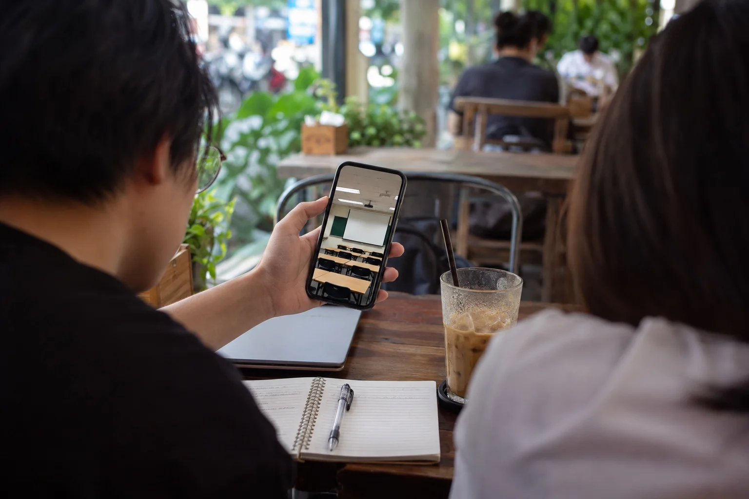 Sinh viên xem ảnh lớp học đại học trên điện thoại tại quán cà phê